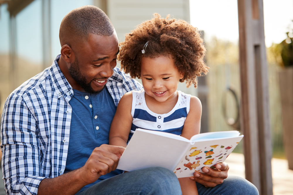 A father reads aloud to his daughter