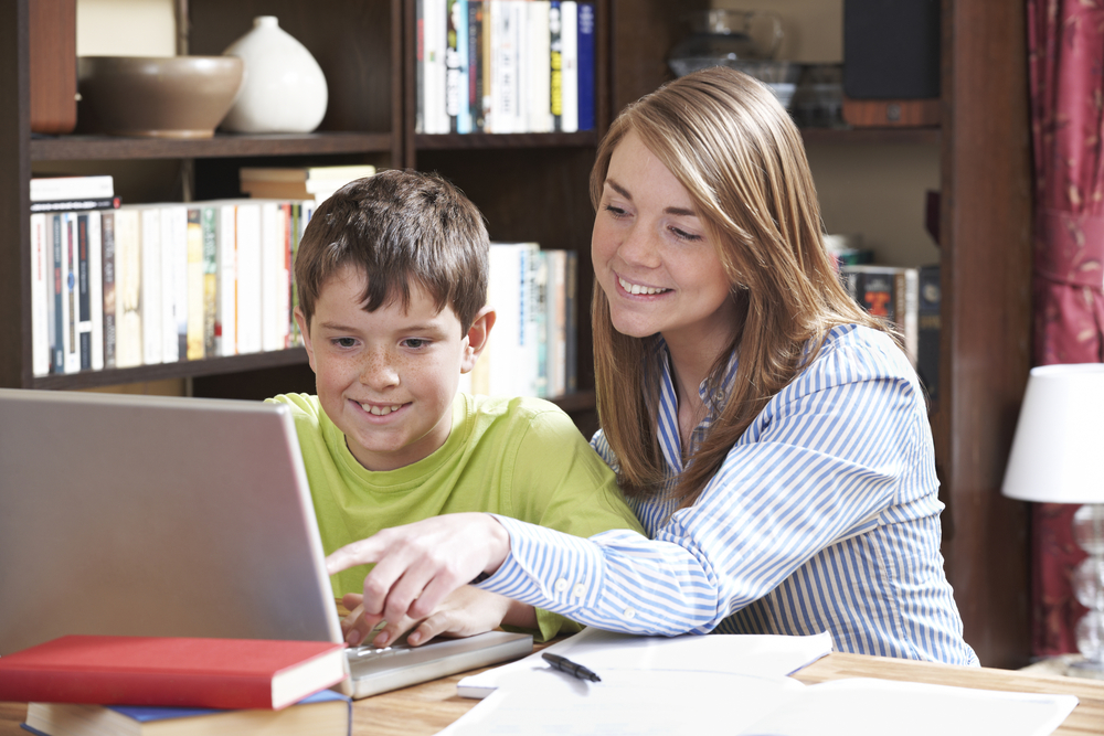 A teen helps a young boy with homework; peer tutoring concept