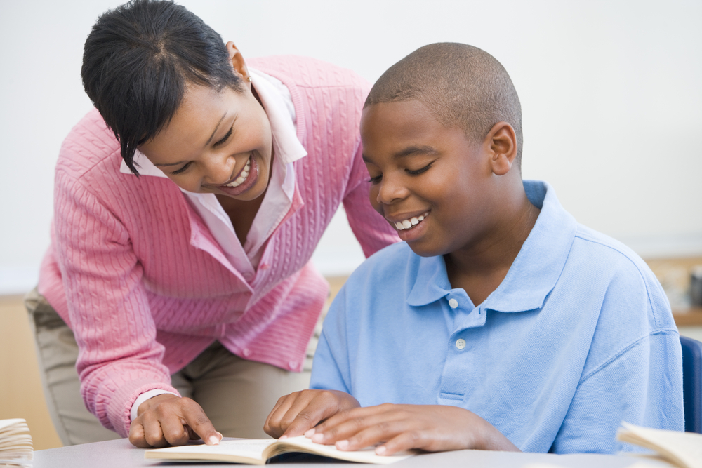 A tutor helps an older elementary student with reading