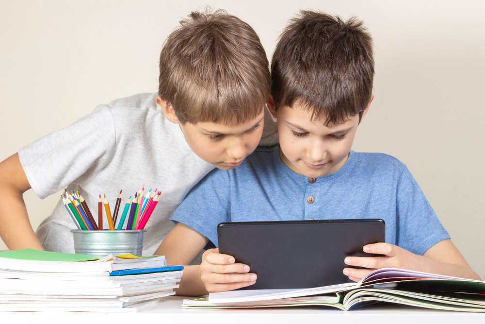 Two brothers using a reading app and practicing reading together