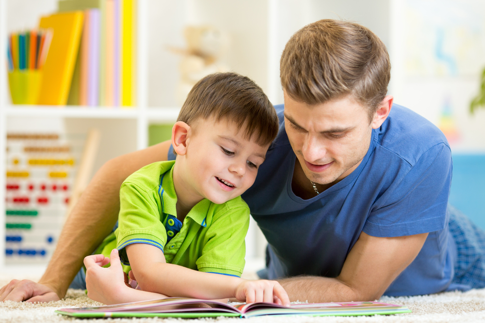 Father and son read together sitting on the floor