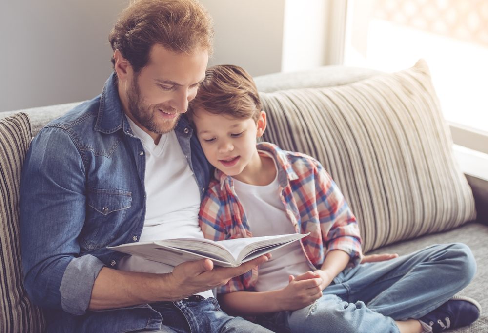 A dad asks his son questions during reading to help child with reading comprehension