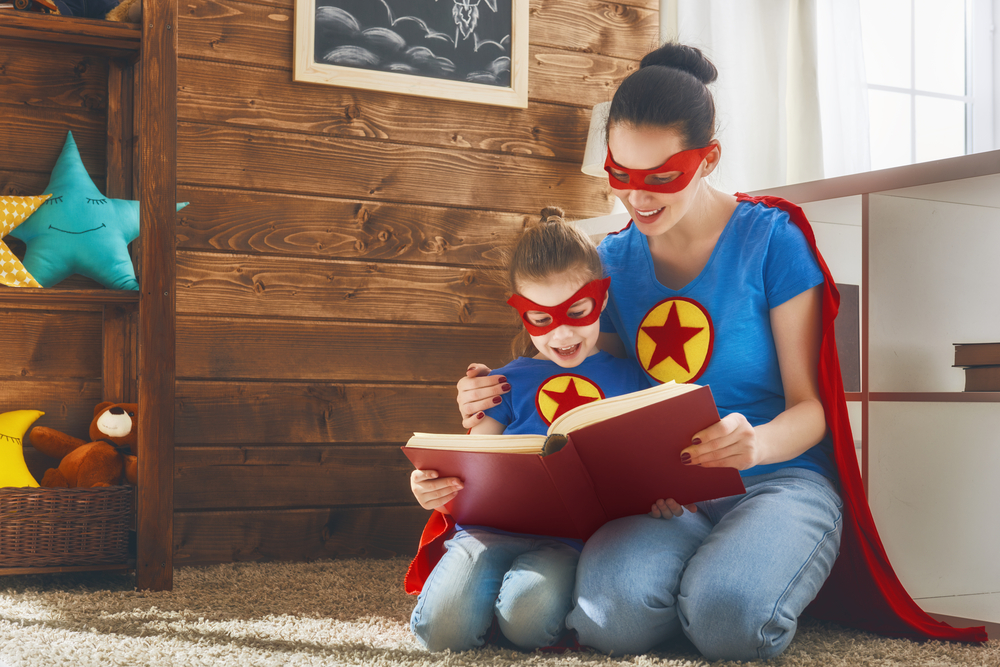 A mother making learning to read fun with superhero costumes