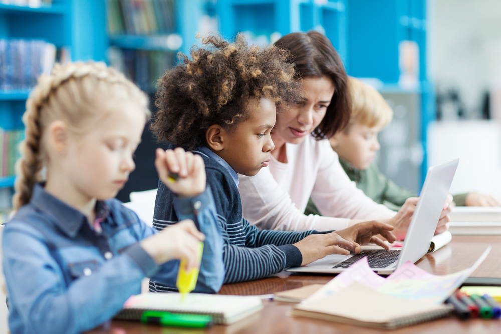 Diverse group of children in a reading intervention program with a teacher.