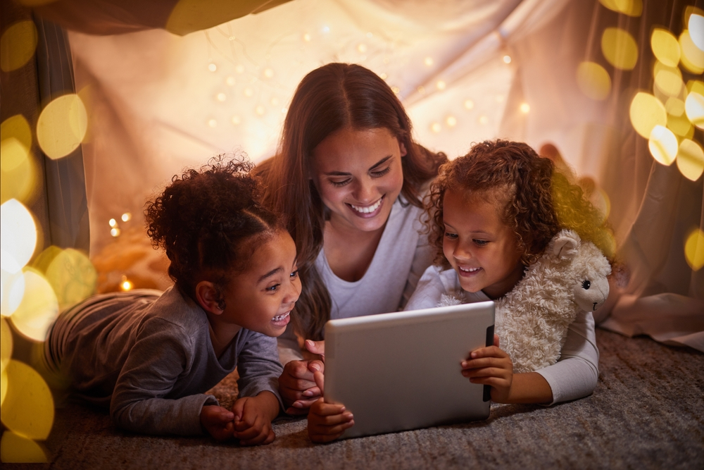 Smiling child developing reading skills using a multisensory educational app with audio and highlighted text.