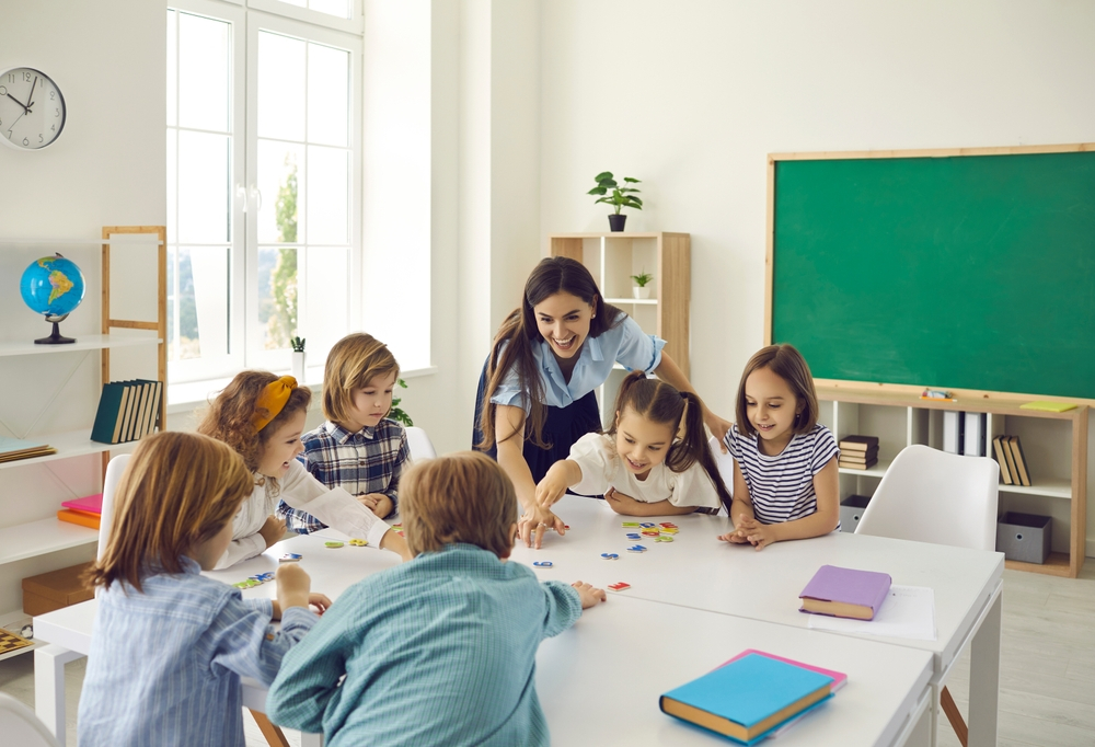 First-grade reading comprehension through phonics, with a teacher guiding a child.