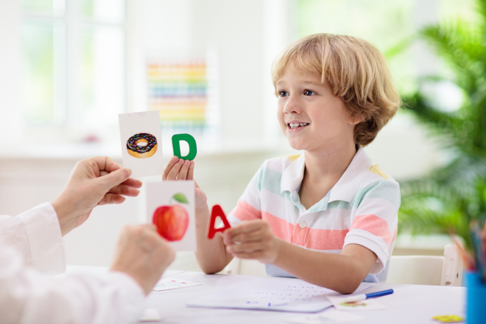 Child engaging in understanding phonics with colorful letters and picture cards, exemplifying effective learning methods