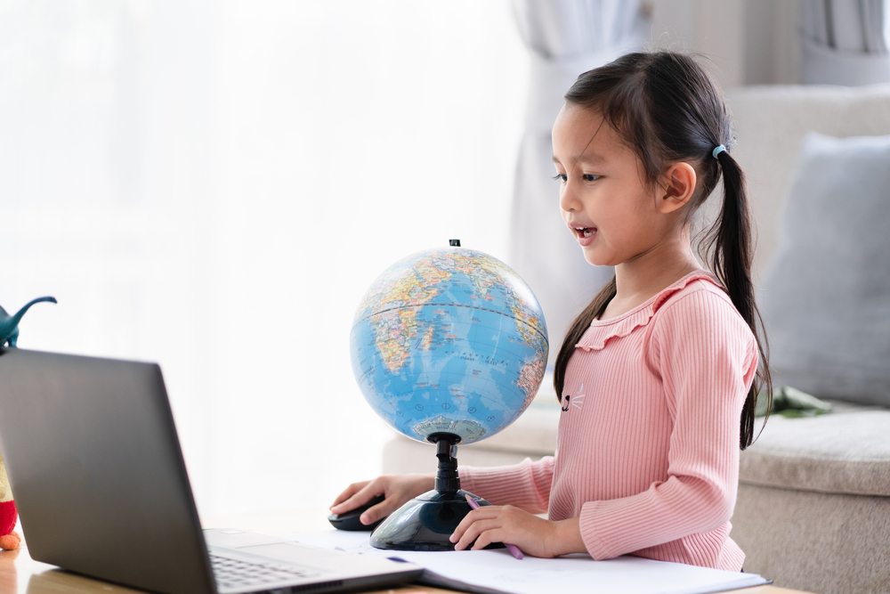 Young Girl Learning Bilingual Literacy Online with Globe and Laptop