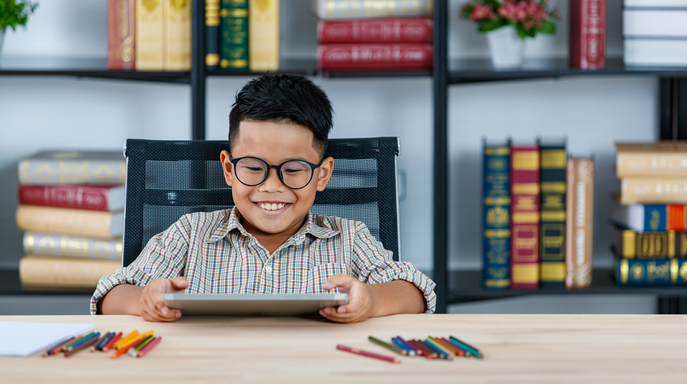 A happy child engaging with a reading app for kids with dyslexia on his tablet