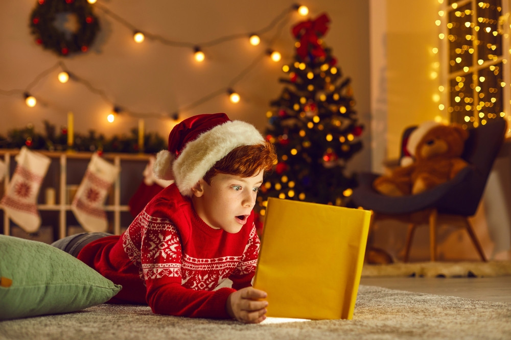 Young boy in Santa hat excitedly using a tablet with Christmas decor, resonating with countdown reading preparation
