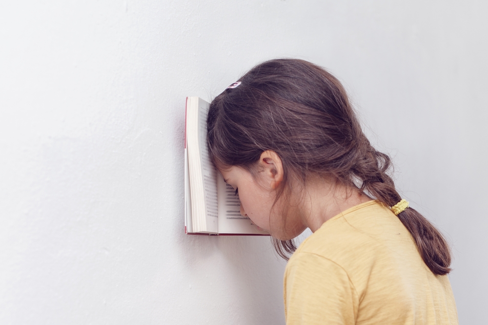 Girl leaning on book reflecting illiteracy rate in California