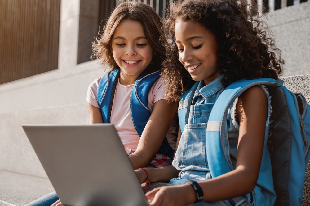 Two children using a laptop for an online reading program in school